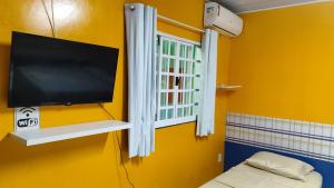 a tv on a yellow wall in a room at House of Colors Hotel in Manaus