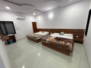 a room with two beds and a flat screen tv at Lord Krishna hotel in Khātu