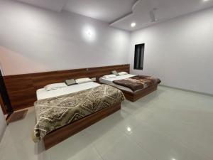 two beds are in a room with a white wall at Lord Krishna hotel in Khātu