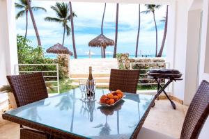 a table with a bowl of fruit and a bottle of wine at DELUXE OCEAN view VILLAS & Apartments with POOL - PLAYA LOS CORALES, BBQ, SPA in Punta Cana
