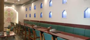 a row of tables and chairs in a room with blue windows at New Hotel Shree Ganga in Shājāpur