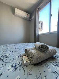 a bedroom with a bed with towels and a remote control at 01 Conforto e estilo-piscina e garagem inclusa in São Leopoldo