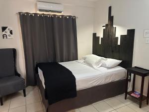a bedroom with a bed with a curtain and a chair at City Garden 2 Apartment in Belize City