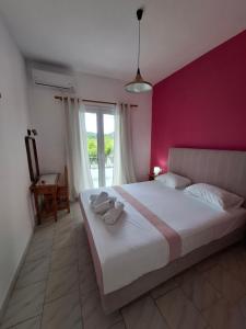 una camera da letto con un letto grande con una parete rosa di Villa Nikitas a Párga