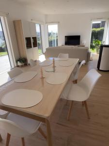 a dining room with a table and white chairs at maison bois in La Forest-Landerneau