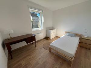 a bedroom with a bed and a desk and a window at maison bois in La Forest-Landerneau