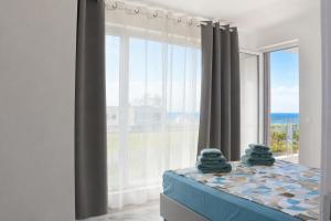 a bedroom with a bed with a large window at Blu Riviera Deluxe in Ahtopol