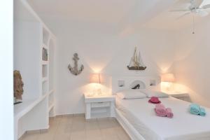 a white bedroom with a white bed and two pink shoes at Yria Holiday Home Paros in Márpissa