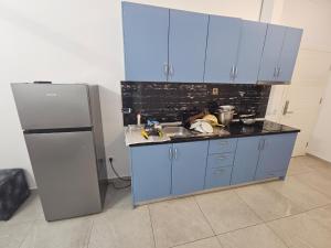 a kitchen with blue cabinets and a sink and a refrigerator at Sea&Stay in Shëngjin