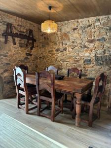 a wooden table with chairs and a stone wall at A casiña do Rieiro in San Pelayo +19 photos