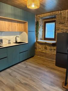 a kitchen with blue cabinets and a window at A casiña do Rieiro in San Pelayo