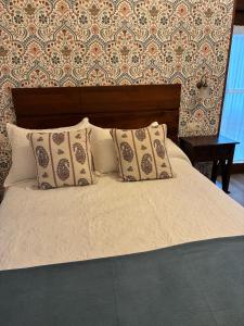 a bed with pillows on it with a wall at A casiña do Rieiro in San Pelayo