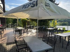 an outdoor patio with tables and chairs and an umbrella at MODRA SOBÓTKA - Perła KASZUB in Ręboszewo