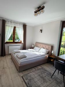 a bedroom with a bed and a desk and windows at Willa Sielanka in Becejły