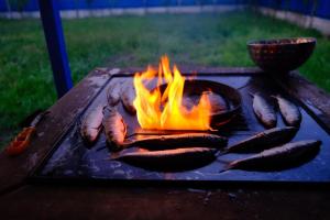 a bunch of sausages cooking on a grill with flames at Casa cu flori in Tulcea