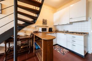 a kitchen with white cabinets and a spiral staircase at La Cami in Torri del Benaco