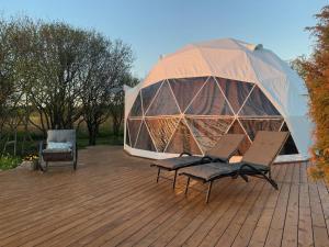 a dome with two chairs and an umbrella on a deck at Saare Glamping Dome House in Salme
