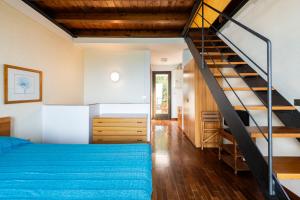 a bedroom with a blue bed and a staircase at La Cami in Torri del Benaco