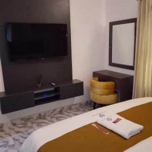 a bedroom with a tv and a bed and a chair at Bluetel Hotel and Suites Limited in Sapele +8 photos