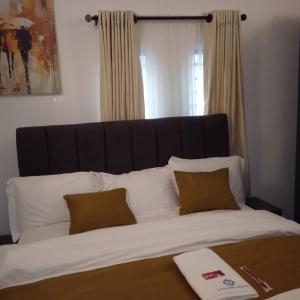 a large bed with white sheets and brown pillows at Bluetel Hotel and Suites Limited in Sapele