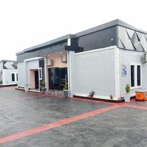 a large white building with a parking lot at Bluetel Hotel and Suites Limited in Sapele