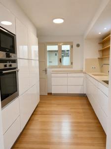 a kitchen with white cabinets and a wooden floor at La Força Penthouse in Girona