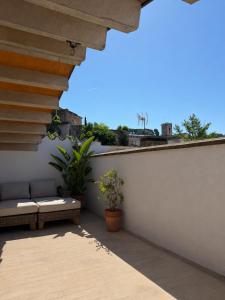 a patio with a couch on a white wall at La Força Penthouse in Girona