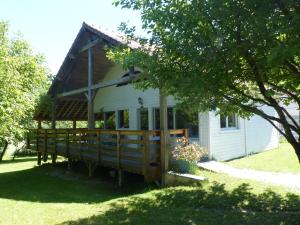 a small white house with a large wooden porch at L'Escapade du Hérisson in Doucier