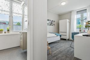 a bedroom with a bed and a kitchen with windows at Mogården in Orkanger