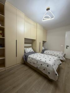 two beds in a room with white cabinets at Cozy Pogradec up in Pogradec