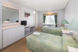 Habitación de hotel con cama y TV en Augusta Hotel Motel en Augusta