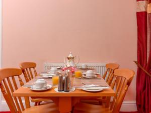 a dining room table with chairs and a wooden table with cups and plates at The Warren Guest House in Carlisle