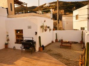 a white building with a grill and a table at Refugio rural en Níjar con jardín privado barbacoa y solarium con vistas únicas in Níjar