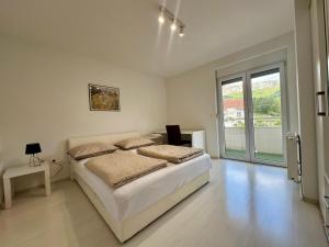 a white bedroom with a bed and a window at Apartman Mara in Solin