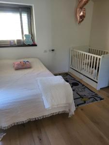 a bedroom with a bed and a crib and a window at Garden villa Raanana in Ra‘ananna