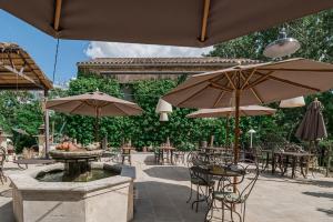 a patio with a fountain and tables and umbrellas at Hôtel O Mamma Mia in Lourmarin