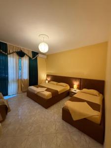 a hotel room with two beds and a window at Vogli's House Apartments & Rooms in Durrës