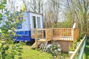 a blue and white tiny house in a garden at Tarka Trail Horsebox - Hot Tub & Pet proof garden in Littleham