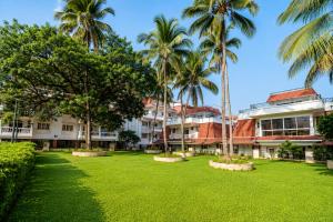 a park with palm trees in front of a building at 400 m from thE beach 1bhk in Colva
