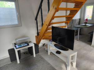 a living room with a tv and a staircase at Melba Vendégház in Dömsöd