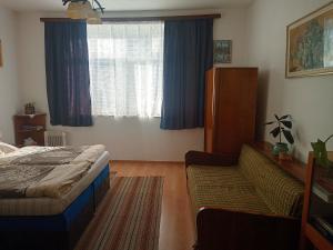 a bedroom with a bed and a couch and a window at Pod kláštorom in Svätý Beňadik