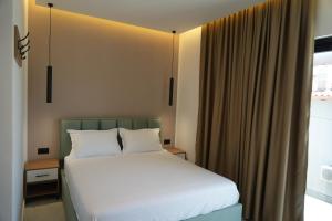 a bedroom with a bed with white sheets and a window at Summer Tale Rooms in Tale