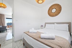 a white bedroom with a bed with towels on it at Sea Breeze Studios in Pervolia
