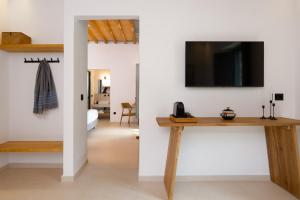a living room with a table and a tv on a wall at Refoulia Eco Suites in Vathi