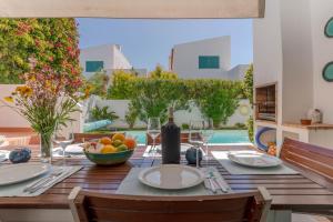 a dining table with a bowl of fruit and wine glasses at L&A Villa Prainha 3 Bedrooms Heated Pool 5 m walking to the beach in Alvor