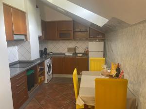 a kitchen with a table and yellow chairs in it at Apartamento Centro das Furnas in Furnas