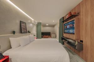 a bedroom with a white bed and a flat screen tv at Gres Apartments Medellin in Medellín