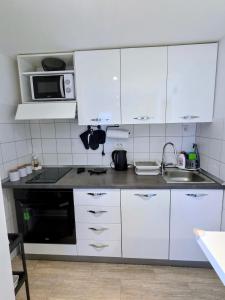 a kitchen with white cabinets and a microwave at Apartman NONO in Splitska