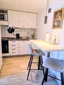 a kitchen with white cabinets and a table and chairs at Apartman NONO in Splitska