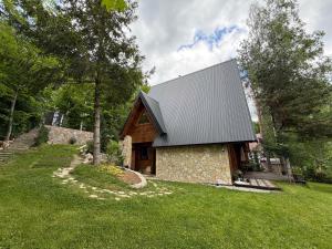 a stone house with a gambrel roof on a lawn at Molika Forest House in Kolašin